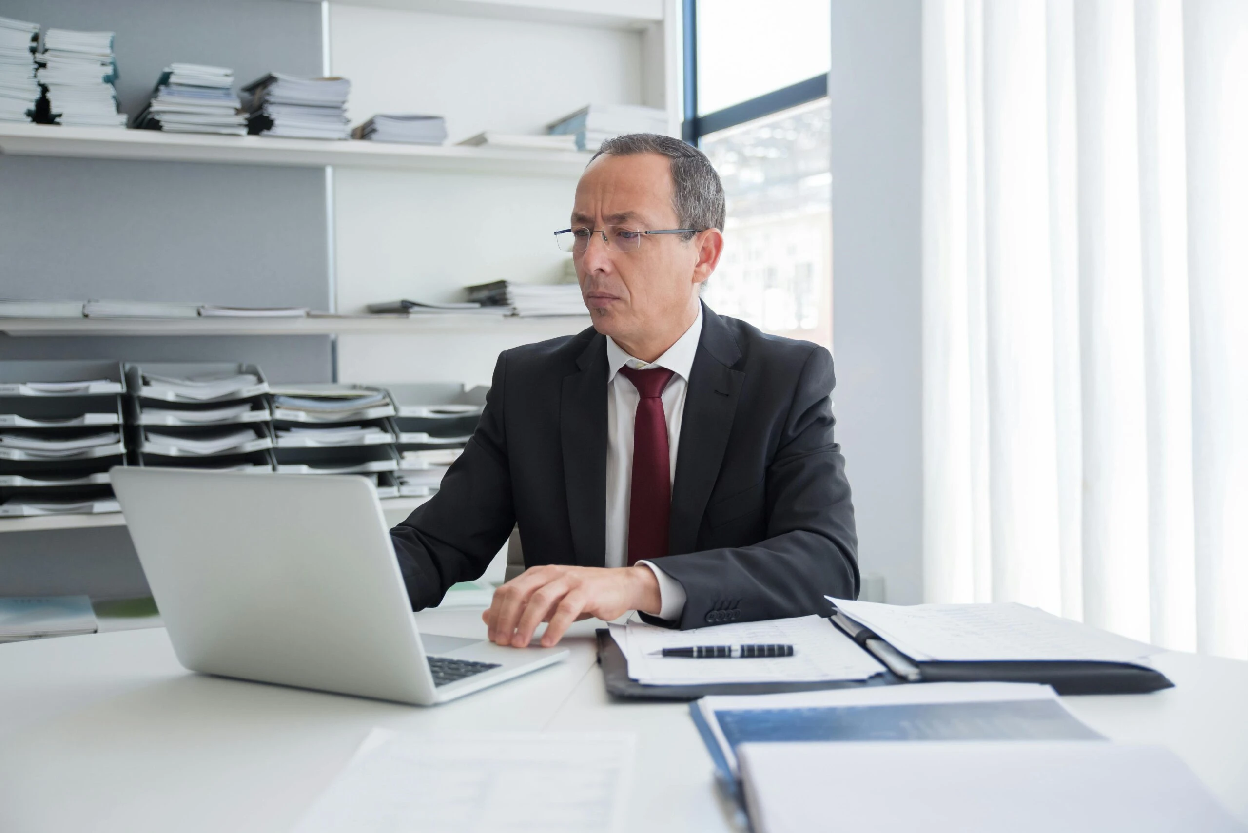 Small business owner reviewing disorganized accounting records on a laptop